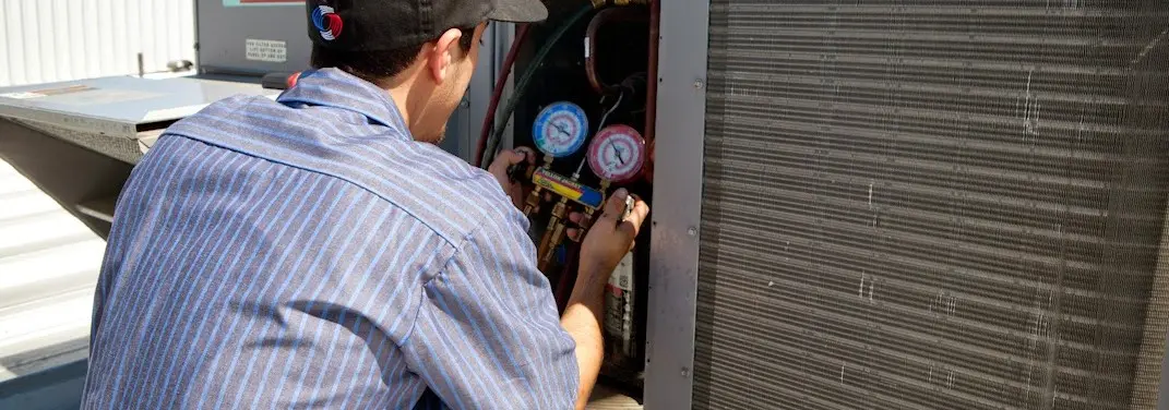 HVAC technician servicing a condenser unit in West Odessa
